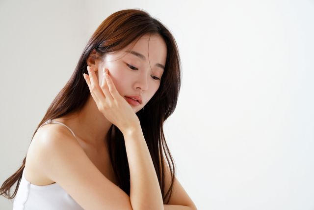 頬に手を当てて悩む女性